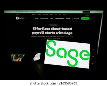 Stuttgart, Germany - 05-29-2022: Person holding cellphone with logo of British software company The Sage Group plc on screen in front of business webpage. Focus on phone display. Unmodified photo.