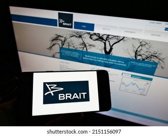 Stuttgart, Germany - 05-30-2021: Person Holding Smartphone With Logo Of Investment Company Brait SE On Screen In Front Of Website. Focus On Phone Display. Unmodified Photo.