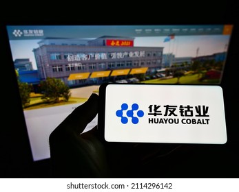 Stuttgart, Germany - 06-06-2021: Person holding mobile phone with logo of Chinese mining company Huayou Cobalt Co. Ltd. on screen in front of web page. Focus on phone display. Unmodified photo.