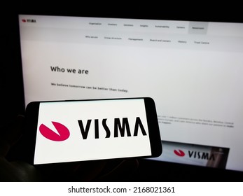Stuttgart, Germany - 06-12-2022: Person holding mobile phone with logo of Norwegian software company Visma AS on screen in front of business web page. Focus on phone display. Unmodified photo.