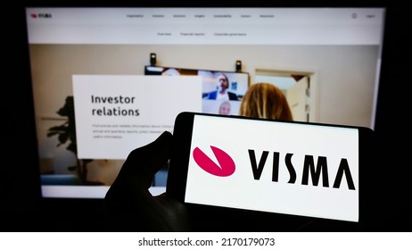 Stuttgart, Germany - 06-12-2022: Person holding smartphone with logo of Norwegian software company Visma AS on screen in front of website. Focus on phone display. Unmodified photo.