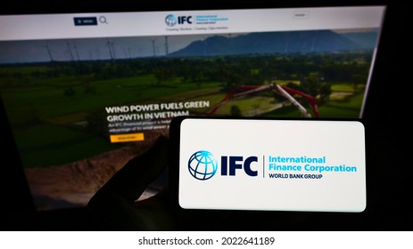 Stuttgart, Germany - 06-13-2021: Person Holding Smartphone With Logo Of Institution International Finance Corporation (IFC) On Screen In Front Of Website. Focus On Phone Display. Unmodified Photo.