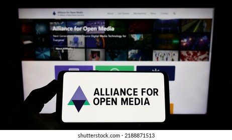 Stuttgart, Germany - 07-10-2022: Person holding smartphone with logo of consortium Alliance for Open Media (AOMedia) on screen in front of website. Focus on phone display. Unmodified photo.