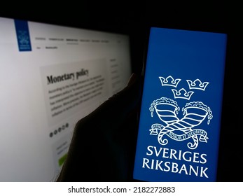 Stuttgart, Germany - 07-16-2022: Person holding smartphone with logo of Swedish central bank Sveriges Riksbank on screen in front of website. Focus on center of phone display. Unmodified photo.