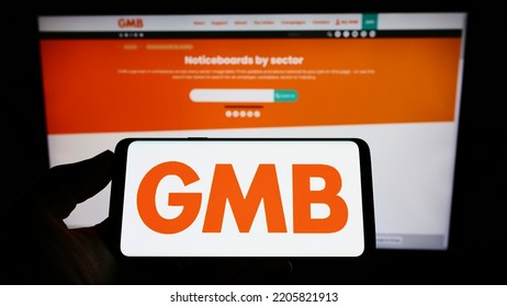 Stuttgart, Germany - 09-19-2022: Person Holding Mobile Phone With Logo Of British Trade Union GMB On Screen In Front Of Web Page. Focus On Phone Display. Unmodified Photo.