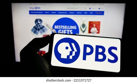 Stuttgart, Germany - 10-01-2022: Person Holding Cellphone With Logo Of American Tv Network Public Broadcasting Service (PBS) On Screen In Front Of Webpage. Focus On Phone Display. Unmodified Photo.