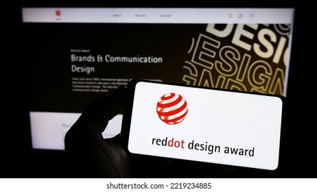 Stuttgart, Germany - 10-15-2022: Person Holding Mobile Phone With Logo Of German International Prize Red Dot Design Award On Screen In Front Of Web Page. Focus On Phone Display. Unmodified Photo.