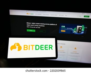 Stuttgart, Germany - 11-12-2021: Person Holding Mobile Phone With Logo Of Singaporean Blockchain Mining Company Bitdeer Group On Screen In Front Of Web Page. Focus On Phone Display. Unmodified Photo.