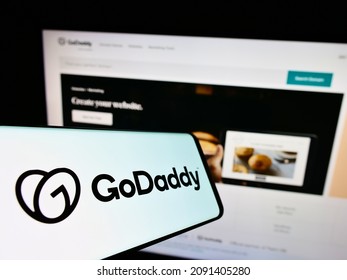 Stuttgart, Germany - 12-11-2021: Cellphone with logo of American web hosting company GoDaddy Inc. on screen in front of business website. Focus on center-left of phone display. Unmodified photo.