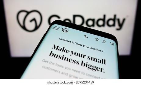 Stuttgart, Germany - 12-11-2021: Mobile phone with webpage of US web hosting company GoDaddy Inc. on screen in front of business logo. Focus on top-left of phone display. Unmodified photo.