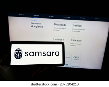 Stuttgart, Germany - 12-11-2021: Person holding cellphone with logo of US cloud software company Samsara Inc. on screen in front of business webpage. Focus on phone display. Unmodified photo.