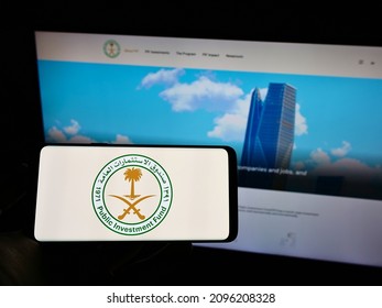 Stuttgart, Germany - 12-18-2021: Person Holding Mobile Phone With Logo Of Saudi Arabian Public Investment Fund (PIF) On Screen In Front Of Web Page. Focus On Phone Display. Unmodified Photo.