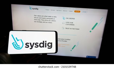 Stuttgart, Germany - 12-19-2021: Person Holding Mobile Phone With Logo Of American Cloud Security Company Sysdig Inc. On Screen In Front Of Web Page. Focus On Phone Display. Unmodified Photo.