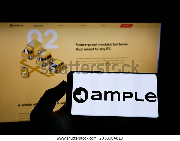 STUTTGART, GERMANY - Aug\
22, 2021: Person holding cellphone with logo of US electric\
mobility company Ample Inc  on screen in front of business webpage \
Focus on phone display\
