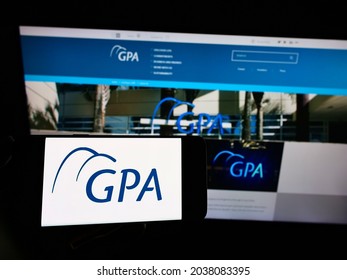 STUTTGART, GERMANY - Aug 30, 2021: Person holding mobile phone with logo of Companhia Brasileira de Distribuicao (GPA) on screen in front of web page  Focus on phone display 