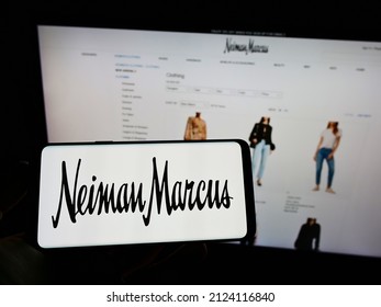 STUTTGART, GERMANY - Jan 09, 2022: Person Holding Mobile Phone With Logo Of American Luxury Retailer Neiman Marcus Group Inc  On Screen In Front Of Web Page  Focus On Phone Display 