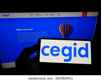 STUTTGART, GERMANY - Jun 22, 2021: Person holding mobile phone with logo of French ERP software company Cegid SA on screen in front of business web page  Focus on phone display 