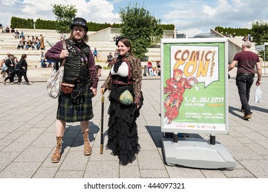 Stuttgart, Germany - June 25, 2016: Two Cosplayers Are Posing During The Comic Con Germany Event In Stuttgart In Front Of The Exhibition Hall On Public Ground Next To The Poster Announcing Next Year