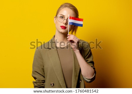 Style blonde woman in jacket with Dutch flag on yellow background