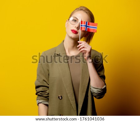 Style blonde woman in jacket with Norwegian flag on yellow background