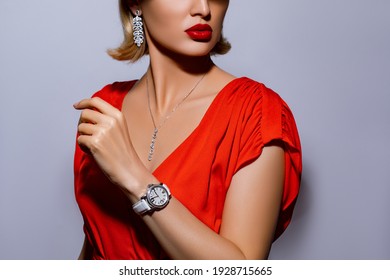 Style Luxury Clock. Close Up Of Woman Hands With Trendy White Watch Decorated With Diamonds And White Crocodile Leather Strap. Girl In Red Dress Trying Watch In A Jewelry Boutique.           