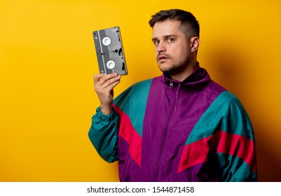 Style Man In 90s Tracksuit With VHS Cassette On Yellow Background