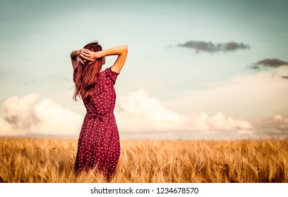 Style redhead girl in red dress tay on yellow wheat field in sunset time and looking forward. Image with cracks and filter - Shutterstock ID 1234678570