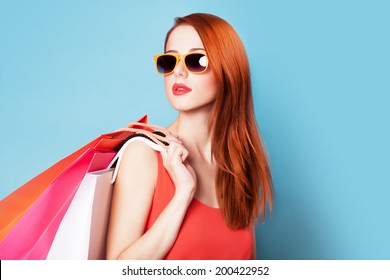 Style redhead women holding shopping bags on blue background.