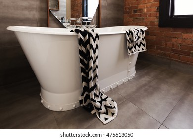 Styled Bath Towel Draped Over A Freestanding Vintage Style Bath Tub