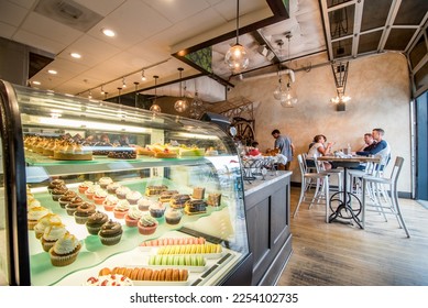 Styled display case filled with refined baked pastry desserts (tarts, tortes, cupcakes, baked goods), in a hip modern bakery or patisserie, perfect for food, chocolatier, pastry, and dessert content - Powered by Shutterstock