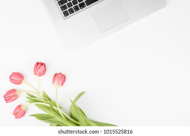 Styled feminine desk workspace with pink tulips and laptop computer. Top view and flat lay of table office desk.