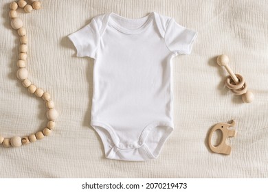 Styled stock photo of clear white baby onesie with wooden toddler toys on ivory napkin for creating mockup for presentation kids sublimation design