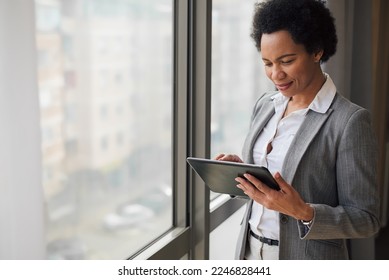 Stylish adult woman in a suit, checking her mail box on her tablet, while at work.