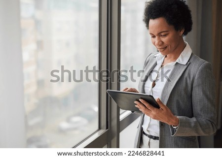 Stylish adult woman in a suit, checking her mail box on her tablet, while at work.
