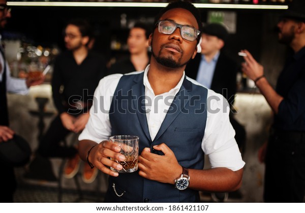 Stylish african american man against group of\
handsome retro well-dressed guys gangsters spend time at club,\
drinking on bar counter. Multiethnic male bachelor mafia party in\
restaurant.