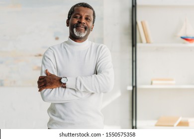 stylish african american man standing with crossed arms and smiling at camera  - Powered by Shutterstock