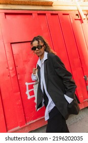 Stylish African American Woman In Oversize Suit And Sunglasses Listening Music On Urban Street In Prague