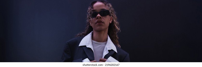 Stylish African American Woman In Sunglasses And Oversize Suit Near Dark Blue Wall, Banner