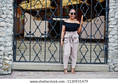 Stylish african american woman at sunglasses with ice cream.