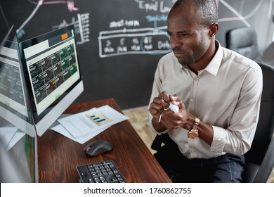 Stylish African Businessman, Trader Sitting By Desk In Front Of Multiple Monitors. He Is Getting Angry While Crumpling Papers. Stock Trading, People Concept.