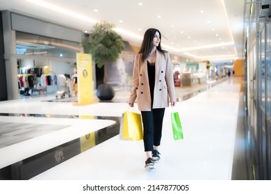 Stylish Arab woman shopping indoor happy in a mall background carrying bags in Dubai looking around