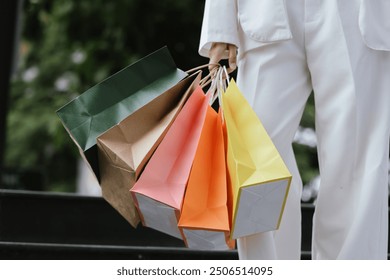 A stylish Asian woman walks happily through a modern city shopping mall. She’s holding luxury bags, enjoying the bustling urban atmosphere, surrounded by fashionable stores and other cheerful shoppers