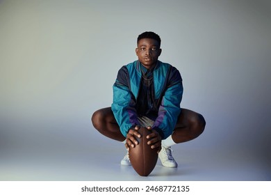 A stylish, athletic African American man crouching with a football. - Powered by Shutterstock