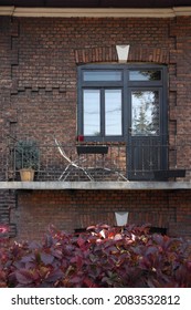 Stylish atmospheric polish balcony with a daybed in the dark brick front facade house, background of autumn grape purple foliage. Rest home place	