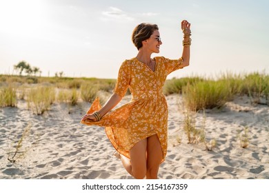 stylish attractive slim smiling woman on beach in summer style fashion trend outfit carefree and happy, feeling freedom, wearing yellow printed dress boho style chic and sunglasses - Powered by Shutterstock