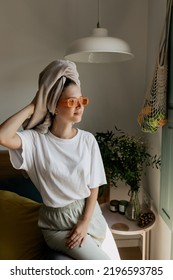 Stylish Attractive Woman Wearing Home Clothes And Bright Glasses With Towel On The Head Posing At Home In Morning. Trendy Girl Preparing For New Day