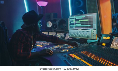 Stylish Audio Engineer / Producer Working in Music Record Studio. Computer Screen Showing User Interface of Digital Audio Workstation Software with Track Song Playing. Uses Control Desk to Create Song