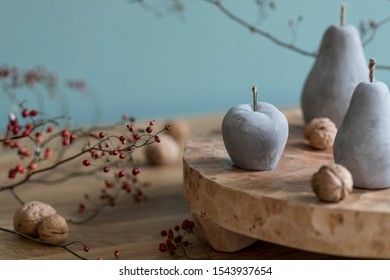 Stylish autumn composition of home decor on living room with wooden fruit tray, cement fruits, nuts and autumn flwoers. Eucalyptus color concpet. Template. Modern decoration. Close up. 