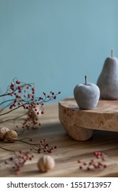 Stylish autumn composition of home decor on living room with wooden fruit tray, cement fruits, nuts and autumn flwoers. Eucalyptus color concpet. Template. Modern decoration. Close up. 