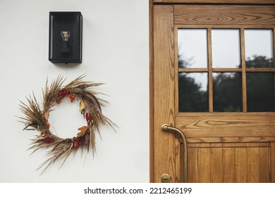 Stylish Autumn Wreath Hanging At Modern Lantern And Wooden Door Outdoor. Fall Decor And Arrangement Of Farmhouse Exterior. Rustic Autumn Wreath With Dried Grass, Berries, Herbs And Leaves